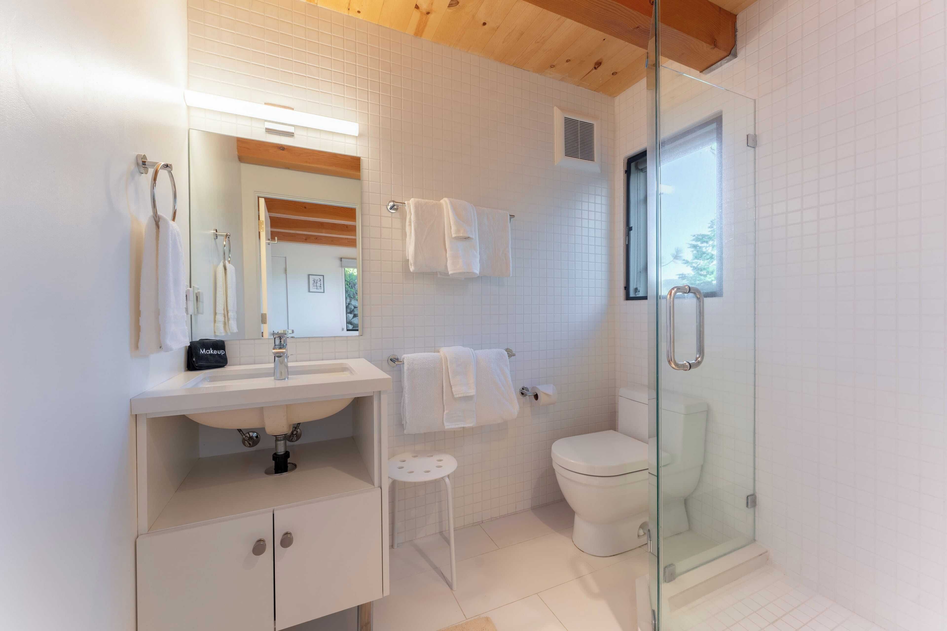 Un bagno moderno con cabina doccia in vetro, un lavandino bianco e un water.
