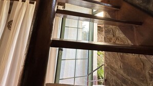A wooden staircase with a stone wall and a window in the background. - Altes Bauernhaus- Erlebnis Vulkaneifel (Sassen)