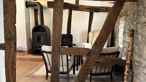 A rustic interior with exposed wooden beams, a stone wall, and a fireplace. - Altes Bauernhaus- Erlebnis Vulkaneifel (Sassen)