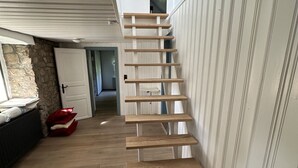 A wooden staircase in a room with a stone wall and a white door. - Altes Bauernhaus- Erlebnis Vulkaneifel (Sassen)