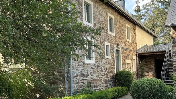 A stone building with a cobblestone pathway leading to a wooden door. - Altes Bauernhaus- Erlebnis Vulkaneifel (Sassen)
