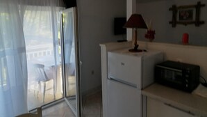 Una cocina compacta con refrigerador, microondas y una pequeña mesa.