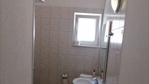 Un baño pequeño con inodoro, lavabo y ducha.