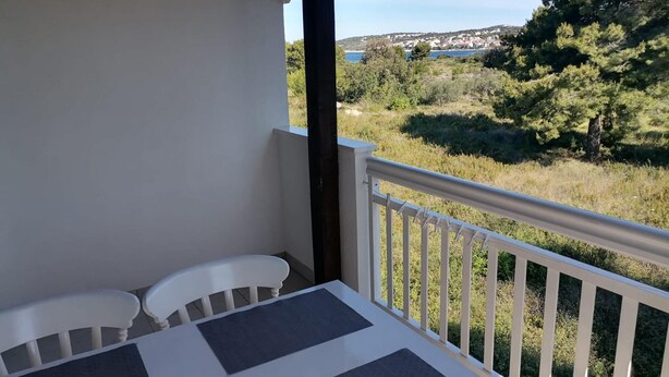 Un balcón con mesa y sillas, con vistas a un paisaje pintoresco de un lago y árboles.