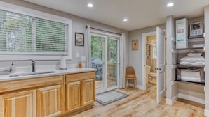 A modern kitchen with wooden cabinets, a large window with blinds, a built-in sink, and a sliding glass door leading to a balcony. - Mt Air Motel (Welches)