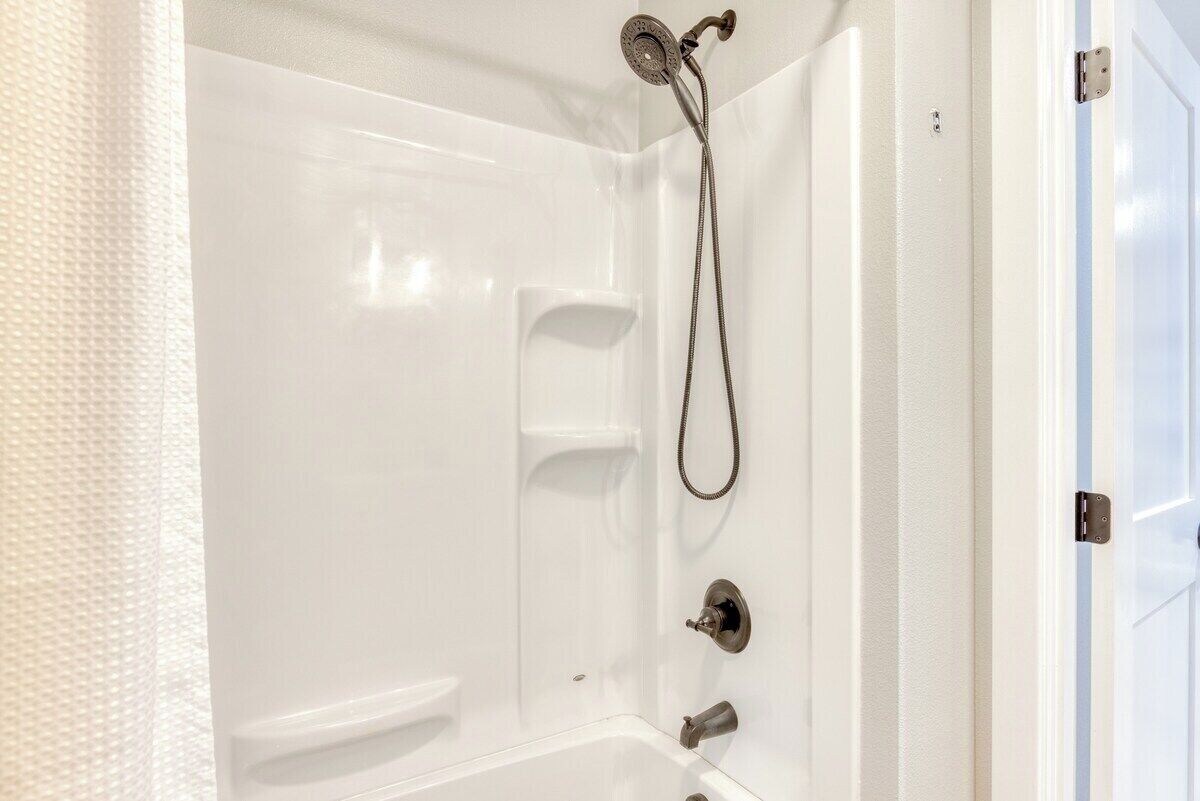 Une baignoire blanche dotée d’un pommeau de douche à main et d’un siège intégré.