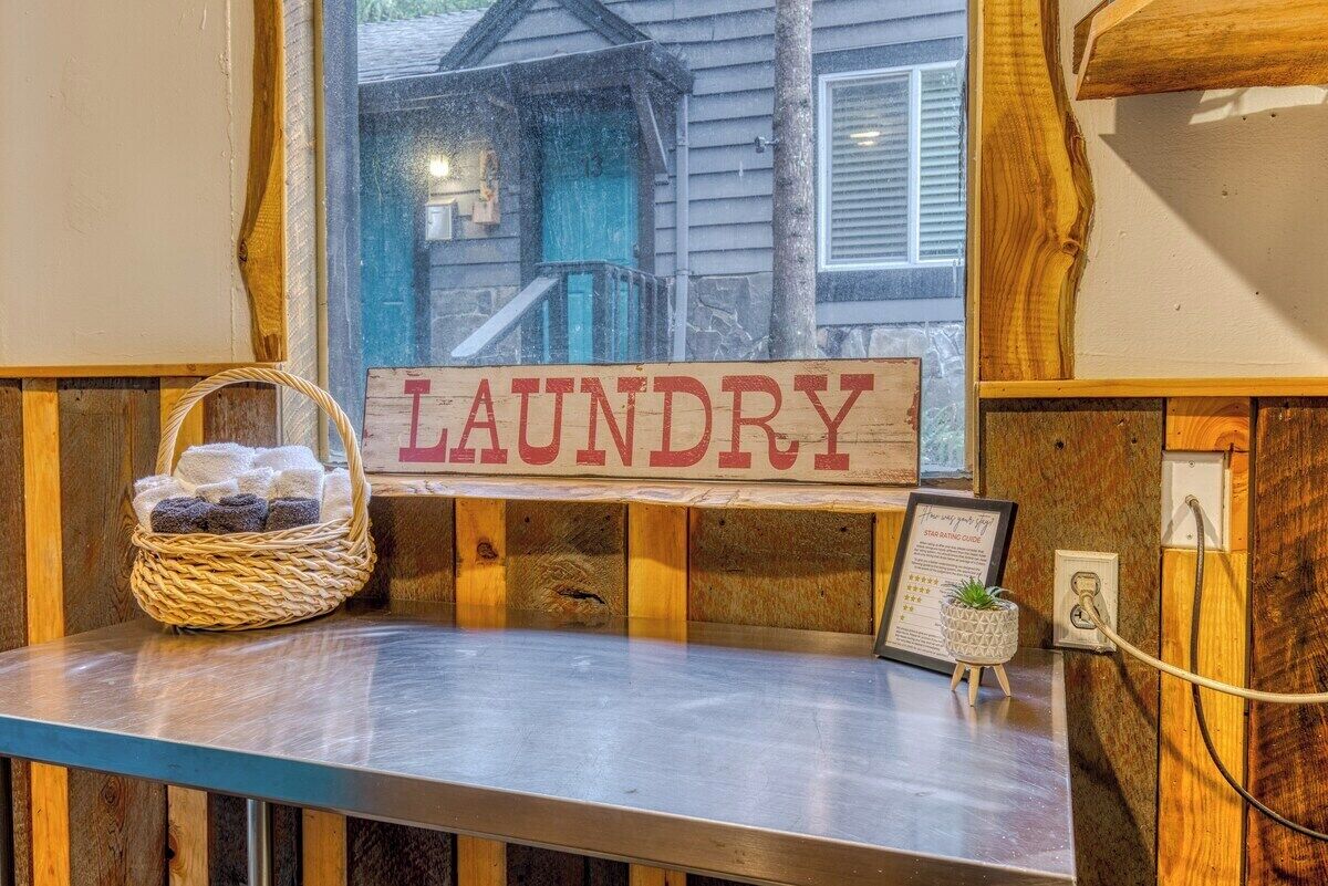 A wooden laundry sign with a basket of towels and a framed certificate on a counter.