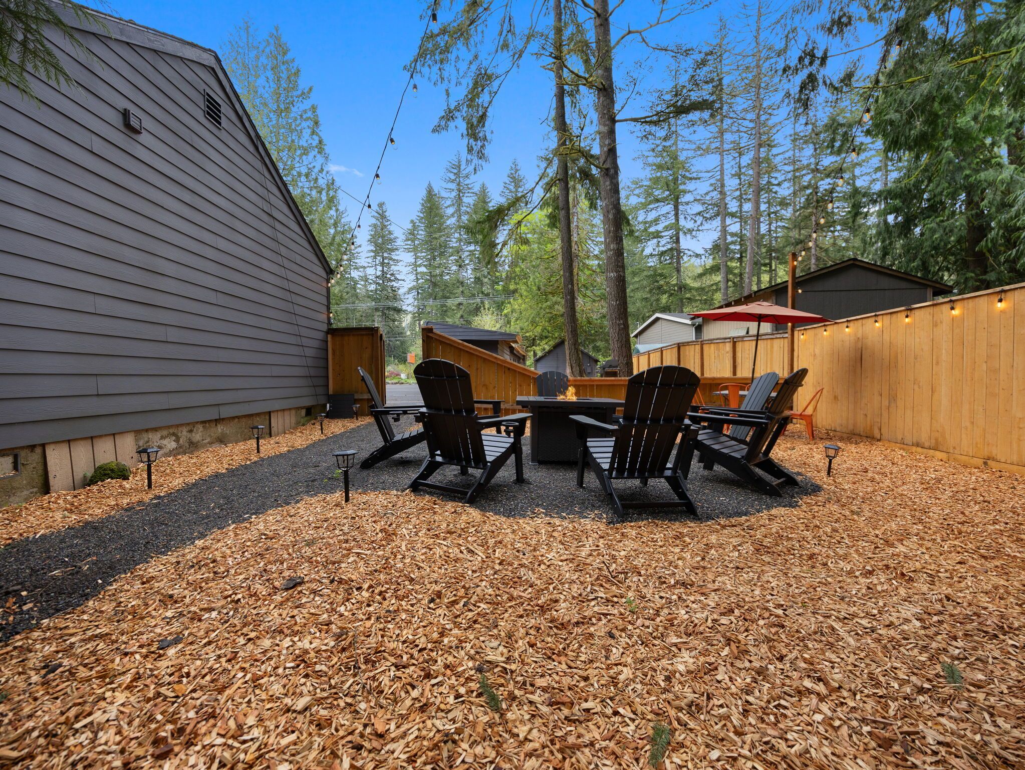 A backyard with a fire pit, outdoor seating, and a wooden deck.