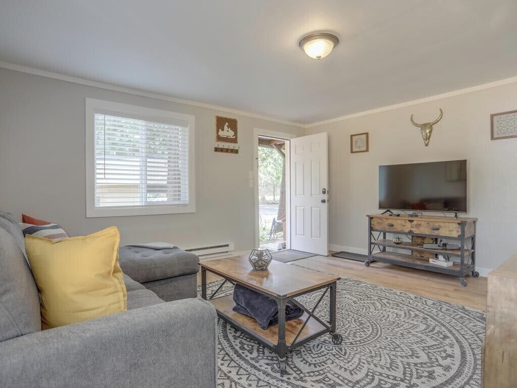 A living room with a gray sofa, a coffee table, a patterned rug, a television, and a door leading outside.