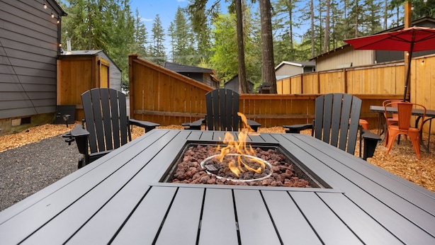 A wooden deck with a metal fire pit table surrounded by chairs. - Mt Air Motel (Welches)