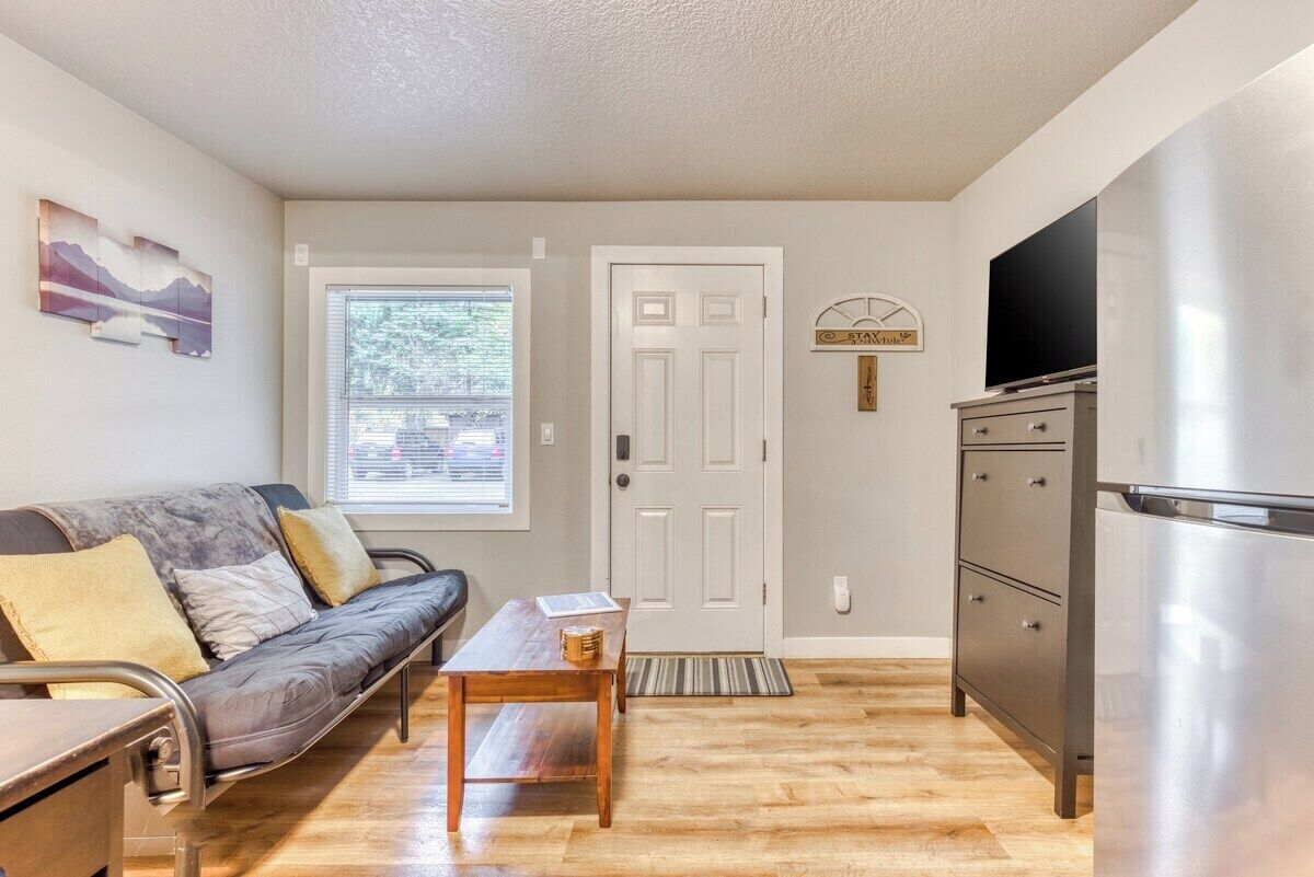 A compact living space with a sofa, a small table, a door, a television, and a refrigerator.