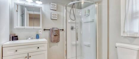 A modern bathroom with a glass shower enclosure, a white sink with a mirror, and a toilet.