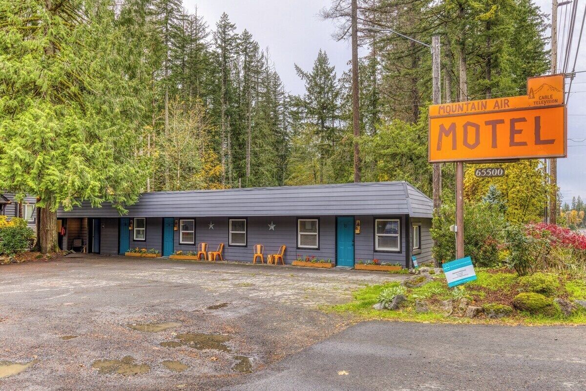 A motel with a dark exterior, a blue door, and a signboard advertising Mountain Air Cable Television.