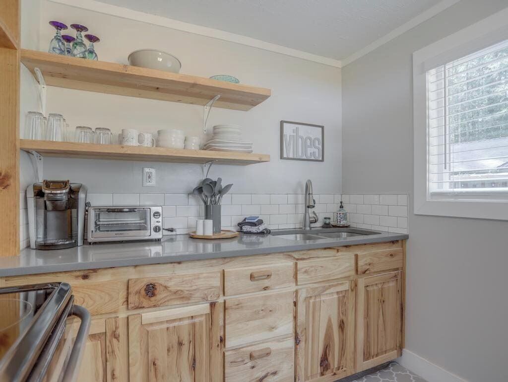 A kitchen with wooden cabinets, a countertop, a toaster, a coffee maker, and a sink.
