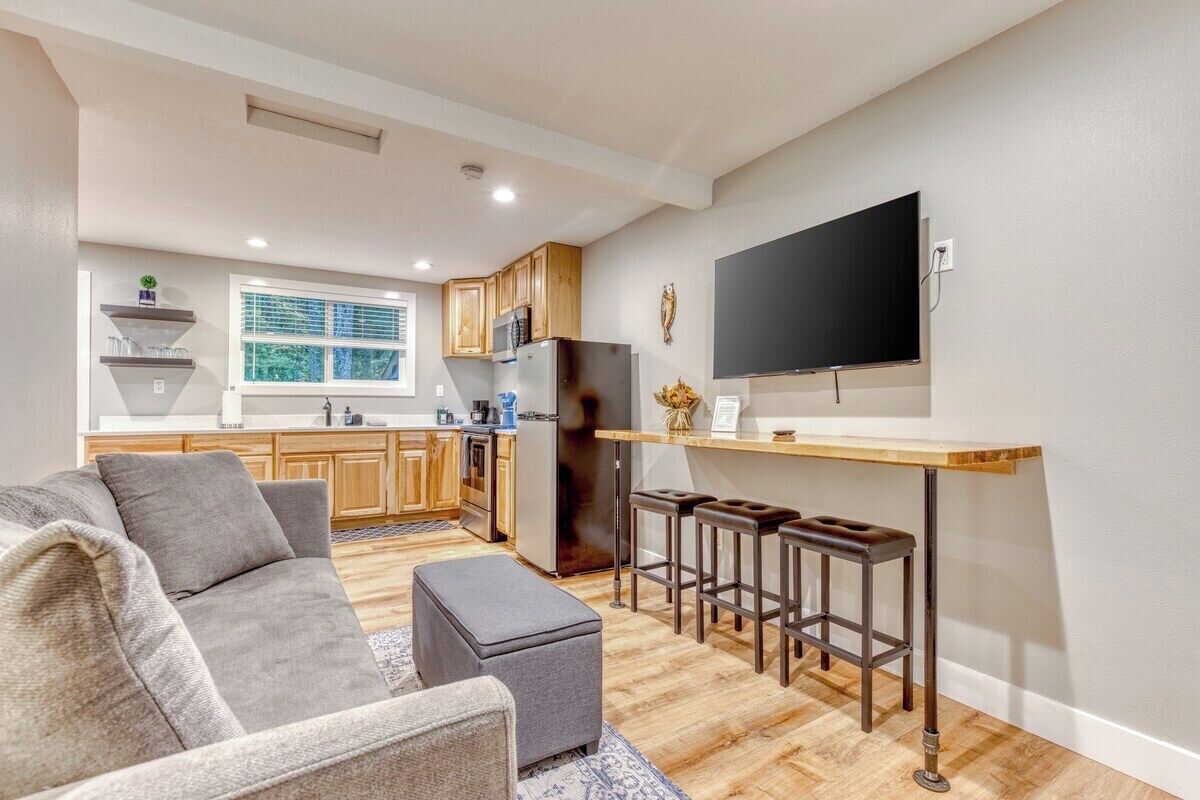 A compact living space with a kitchenette, a sofa, a coffee table, and a TV mounted on the wall.