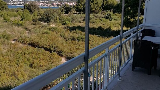 A covered balcony with a view of a coastal landscape, including a body of water and distant buildings. - Apartments Libertas - One Bedroom Apartment with Terrace and Sea View - (5) (Rogoznica)
