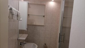 Ein kleines Badezimmer mit Waschbecken, Spiegel und Handtuchhalter.