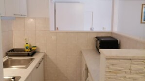 Una cocina compacta con un lavamanos, un microondas y un ventanal sobre la encimera.