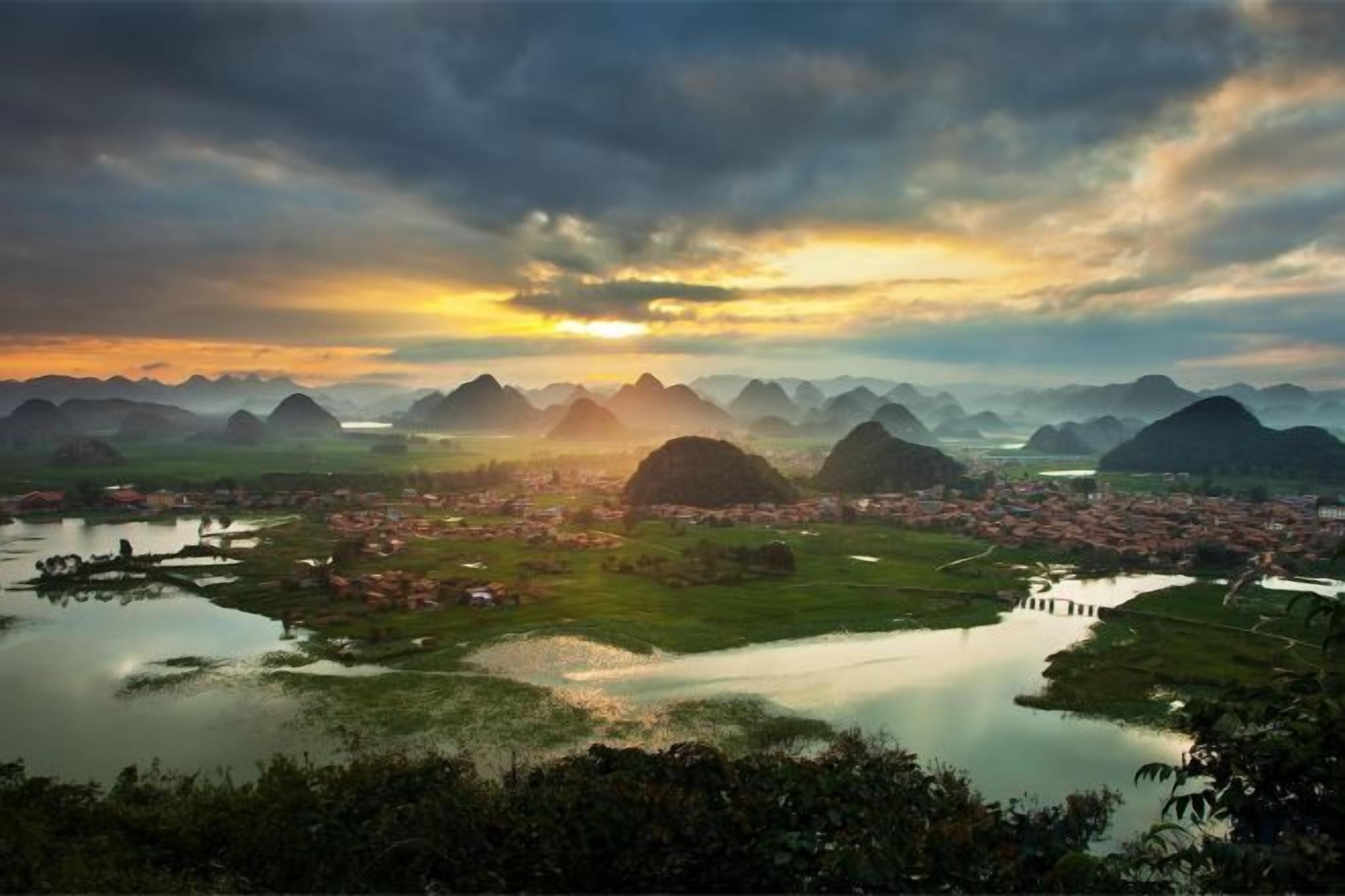 A panoramic view of a mountainous landscape with a river and a small town.