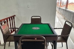 Une table de billard recouverte d’un drap vert, entourée de quatre chaises à ossature métallique.