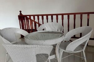 A wicker dining set with four chairs and a table, positioned in front of a wooden staircase.