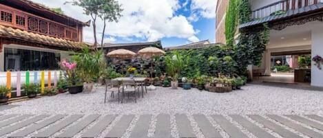 A courtyard with a gravel path, outdoor seating, and potted plants.
