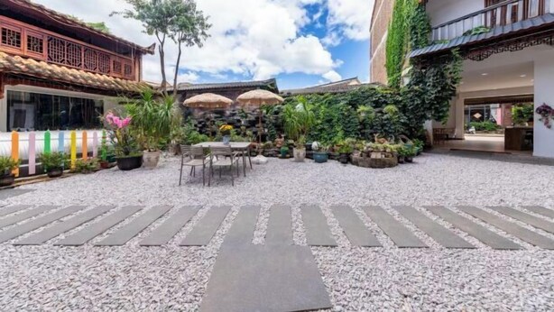 A courtyard with a stone pathway, potted plants, and outdoor seating. - Puzhehei Qingshui Lianyi Boutique Inn (Qiubei)