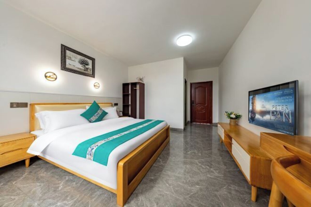 Habitación de hotel con cama, escritorio, televisor y puerta.