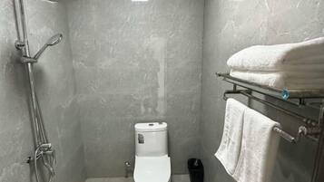 Un baño con ducha, inodoro y perchero para toallas.