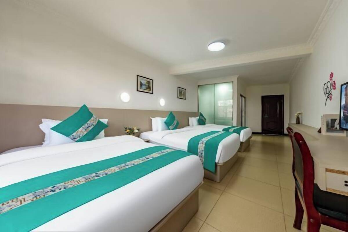 Une chambre d’hôtel avec deux lits, une chaise rouge et une porte donnant sur une autre pièce.