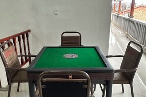 Una mesa de billar con superficie de fieltro verde, rodeada por cuatro sillas metálicas.