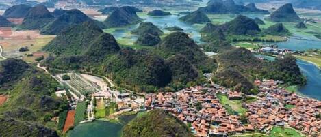 An aerial view of a town with a river, surrounded by hills and greenery.