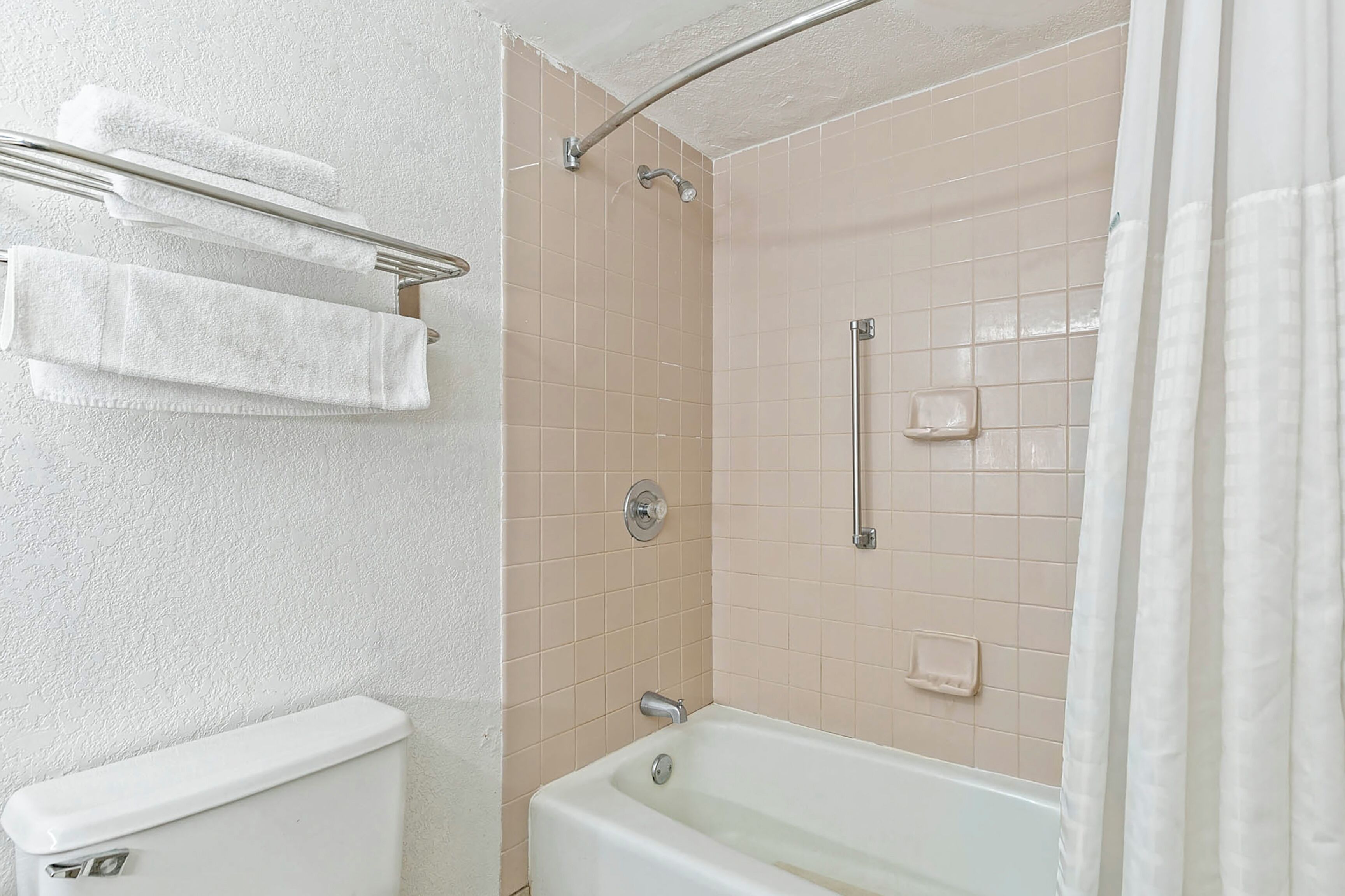 Ein Badezimmer mit Toilette, Badewanne, Dusche und Handtuchhalter.
