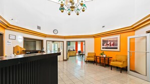 A hotel lobby with a reception desk, seating area, and a kitchen visible in the background. - Moonlight Inn Hotel O Hattiesburg, MS (Hattiesburg)