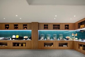 Una cocina moderna con armarios de madera, salpicadero color aguamarina y diversos electrodomésticos.