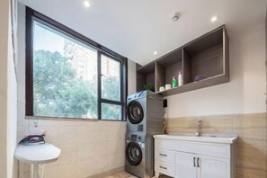 Un área de lavandería compacta con lavadora, lavamanos y ventana.
