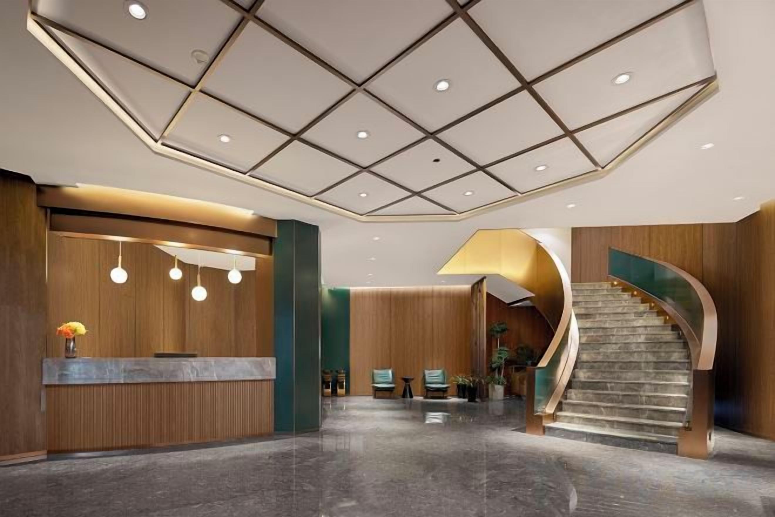 Un moderno vestíbulo de hotel con mostrador de recepción, zona de estar y una escalera curva.