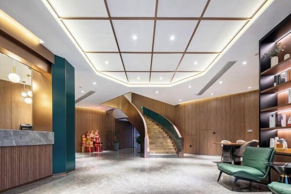 Eine moderne Lobby mit einer geschwungenen Treppe, einem Empfangsbereich und einer Sitzecke.