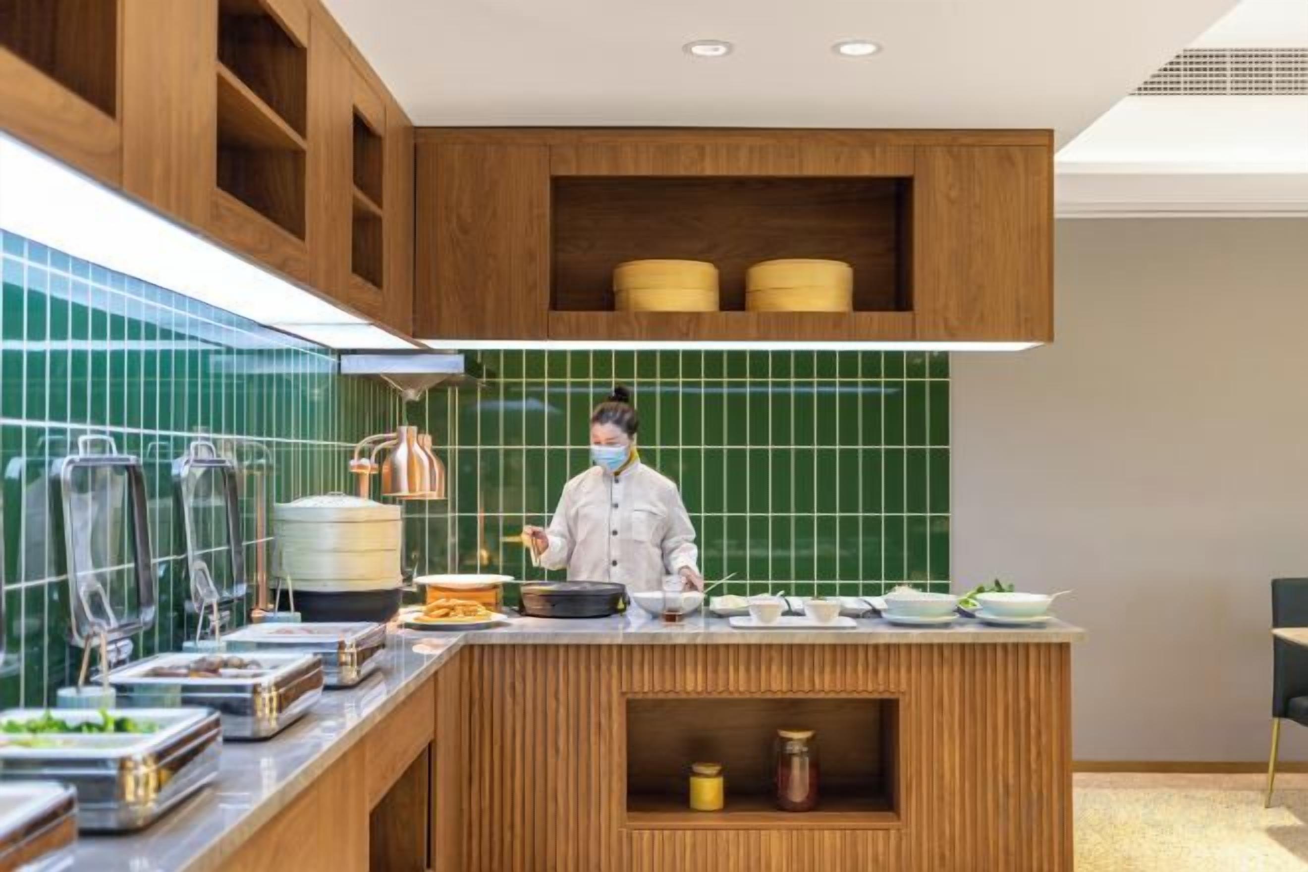 A modern kitchen with a chef preparing food, equipped with various cooking utensils and appliances.
