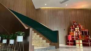 Un moderno vestíbulo de hotel con una escalera de mármol, paneles de madera y una pila de cajas de regalo.