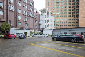 Un estacionamiento con varios autos, un edificio de varios pisos y cielo despejado.