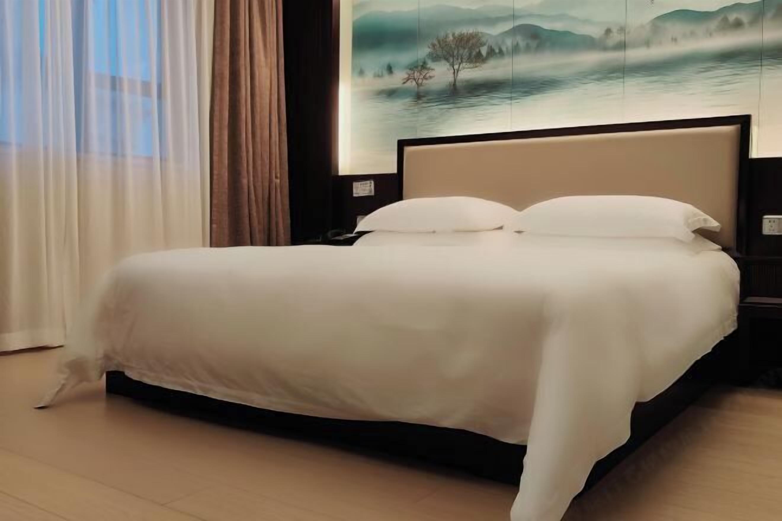 Una cama bien hecha con una colcha blanca en una habitación de hotel.