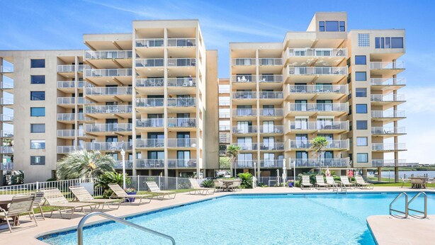 A modern hotel with a swimming pool, multiple balconies, and sun loungers. - Compass Point 201 Pet-friendly for fee Boat Ramp (Gulf Shores)