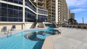 Une piscine avec des marches permettant d’y accéder, entourée d’une terrasse en béton et de chaises longues.