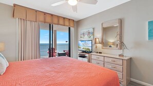 A bedroom with a large bed, a ceiling fan, a TV, a dresser, and a view of the ocean. - Windward Pointe 1104 Amazing Views A Amenities (Orange Beach)