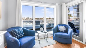 Un balcón con dos sillones azules, una mesita y vista al puerto deportivo.
