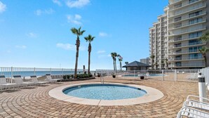 A circular pool with a brick border, surrounded by lounge chairs and palm trees, with a high-rise building in the background. - Windward Pointe 1401-large Balcony Best Views (Orange Beach)