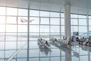 An airport terminal with large windows, a central column, and rows of seats. - Jingyi guoji Hotel（Guangzhou Huadu Sunac Cultural Tourism Store） (Guangzhou)