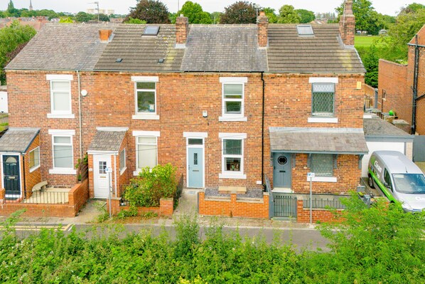 A two-story brick house with a front garden, a garage, and a parked van. - Cosy Green End Retreat (Wakefield)