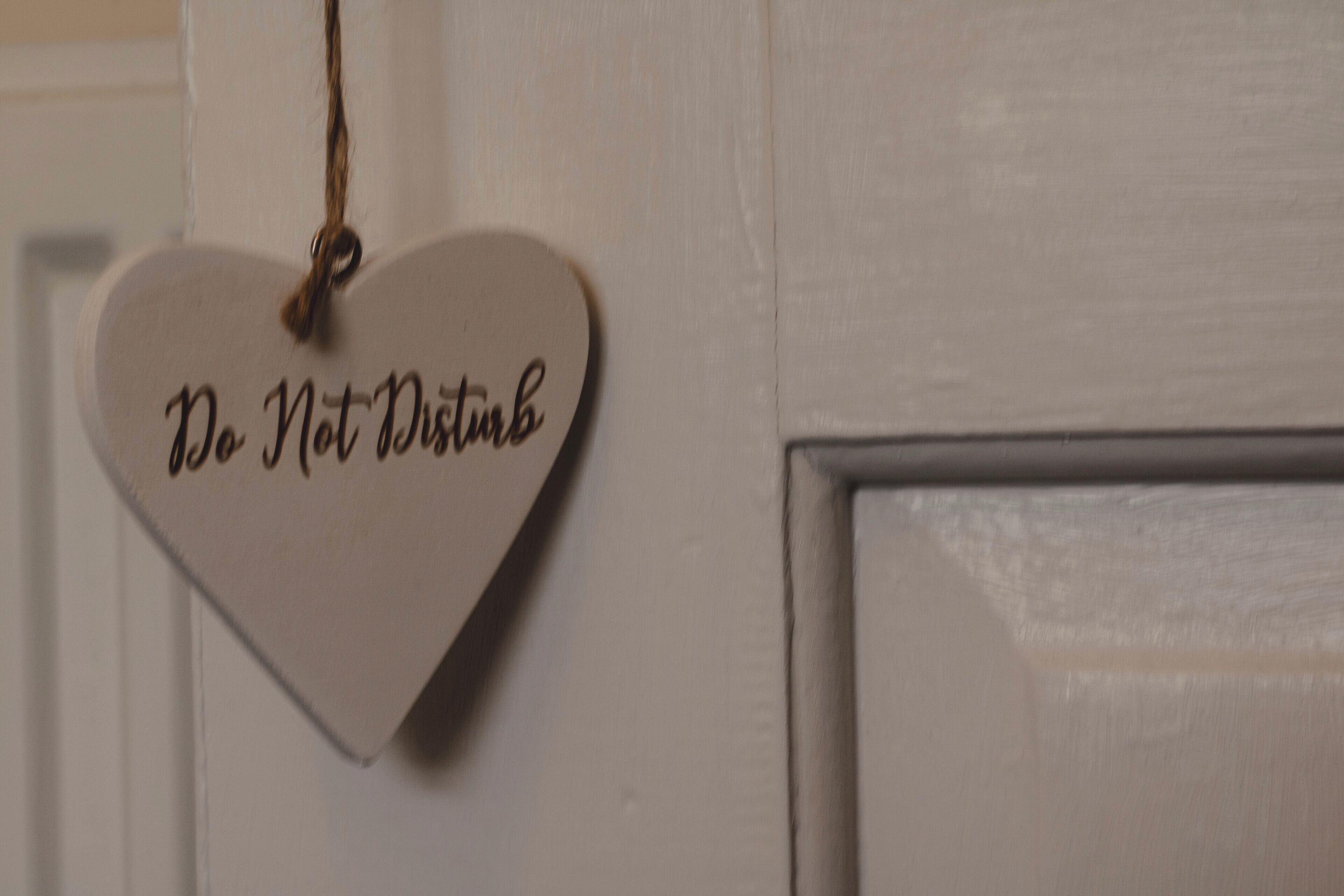 A heart-shaped sign with the text "Do Not Disturb" hanging on a door.
